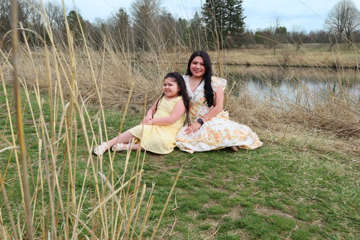 Outdoor photoshoot in a natural field setting with tall grass and trees in the background.