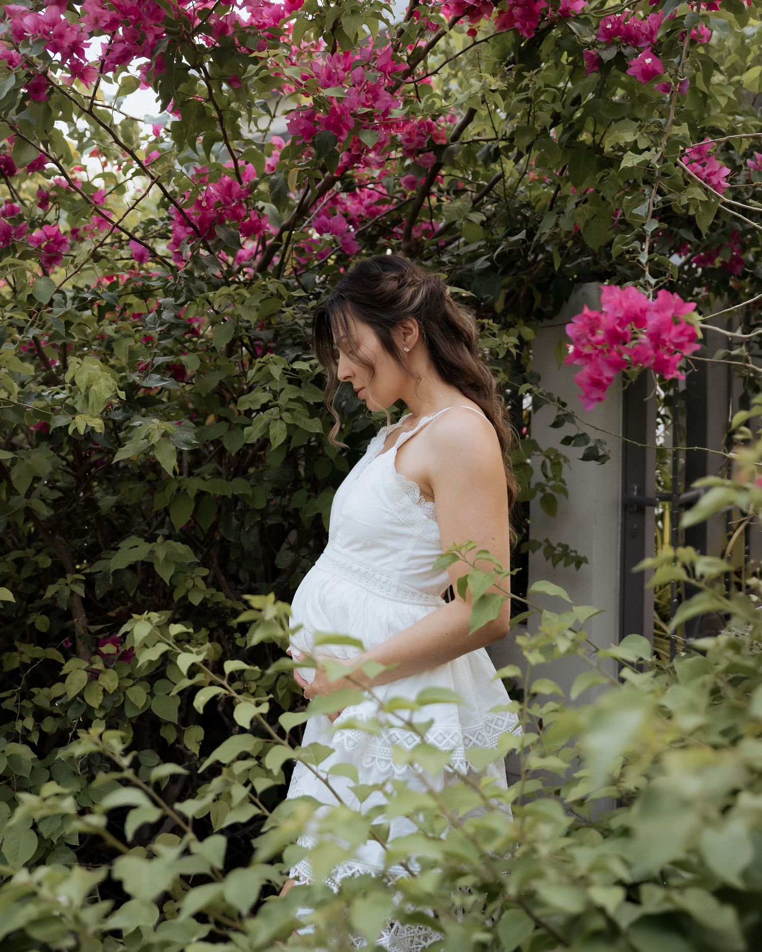 Outdoor maternity photoshoot in Dubai garden with natural light and floral background