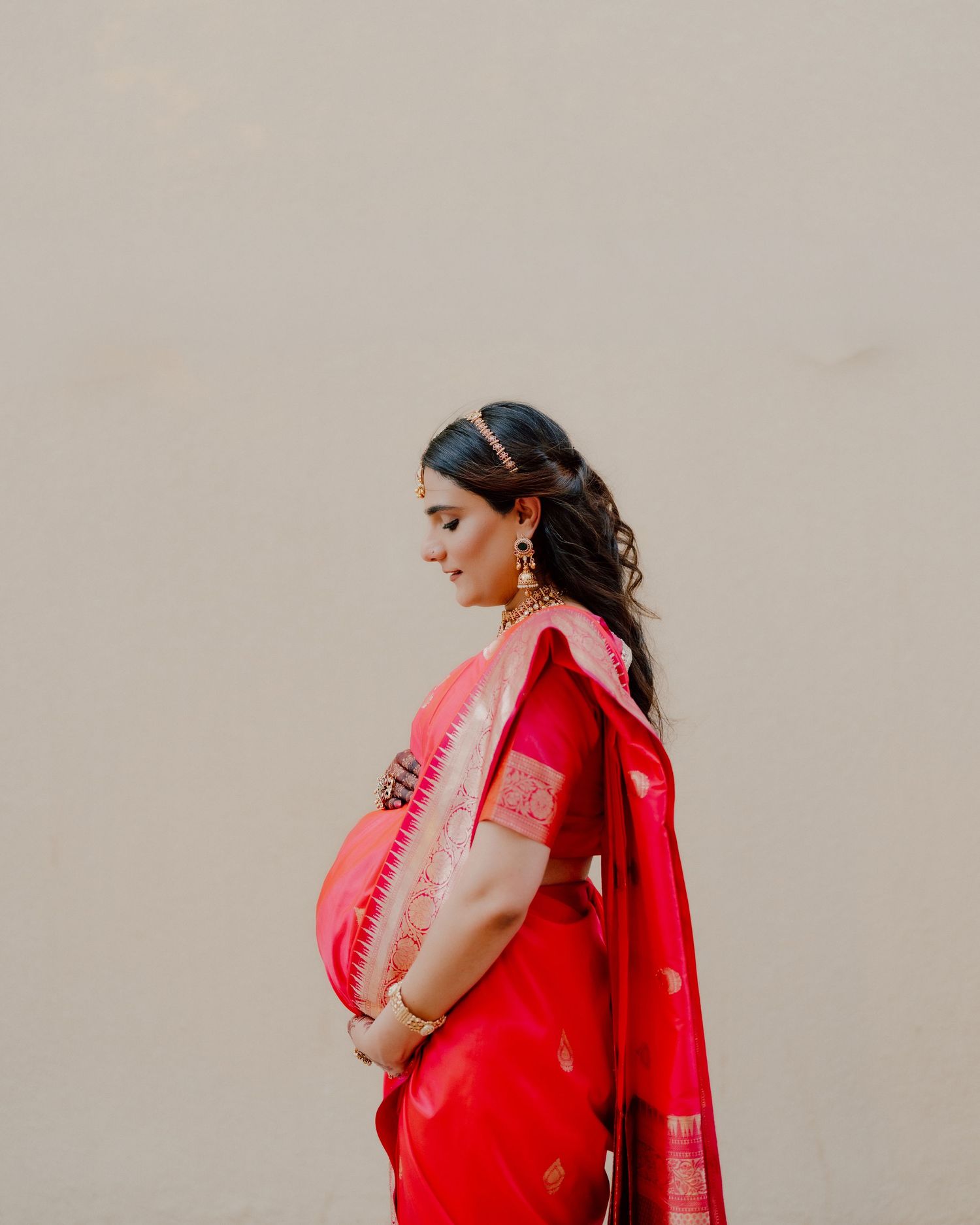 Maternity photoshoot in Dubai – South Asian woman in traditional pink sari, studio portrait