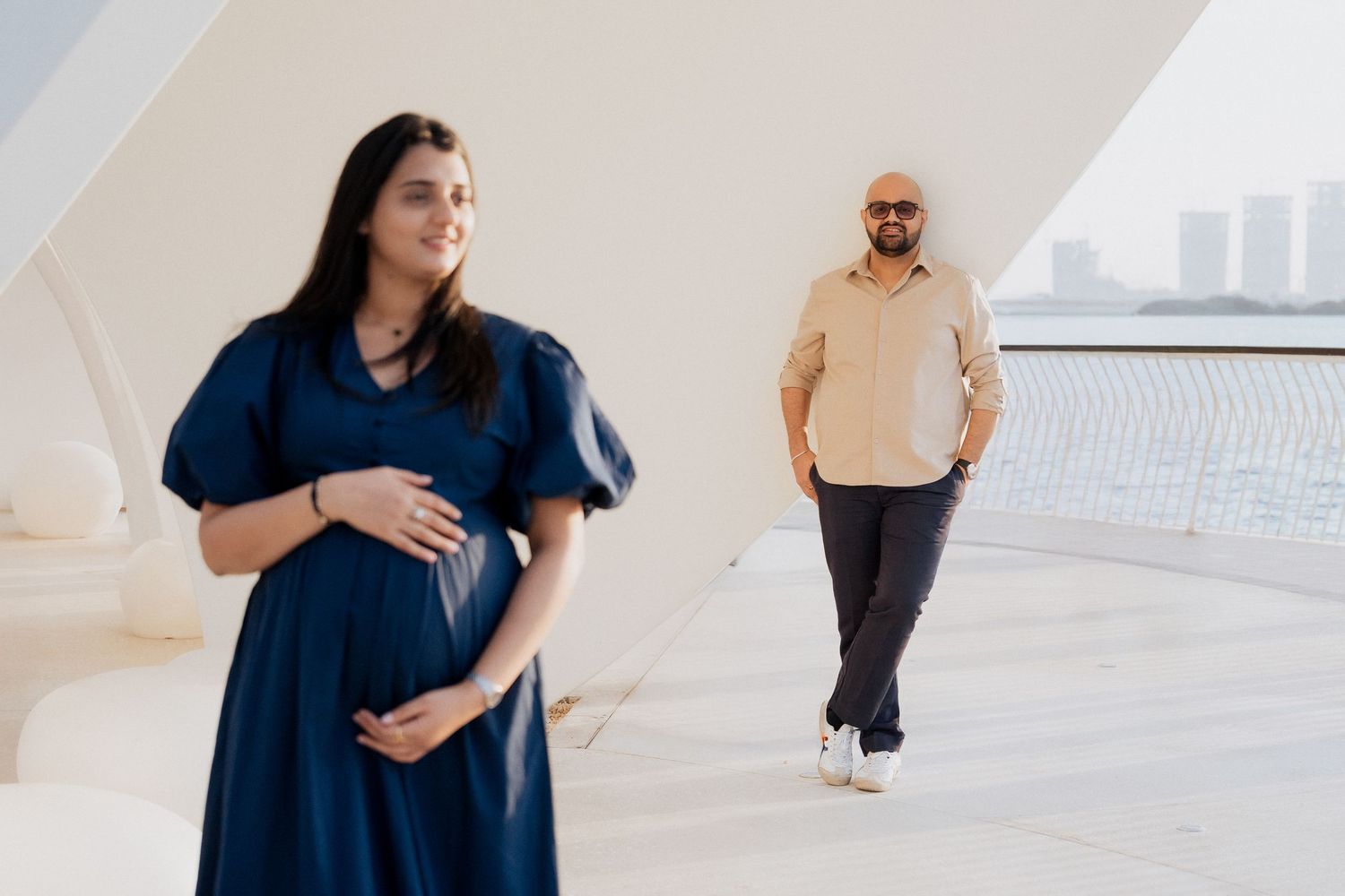 Candid maternity photoshoot in Dubai with couple walking in modern architectural location