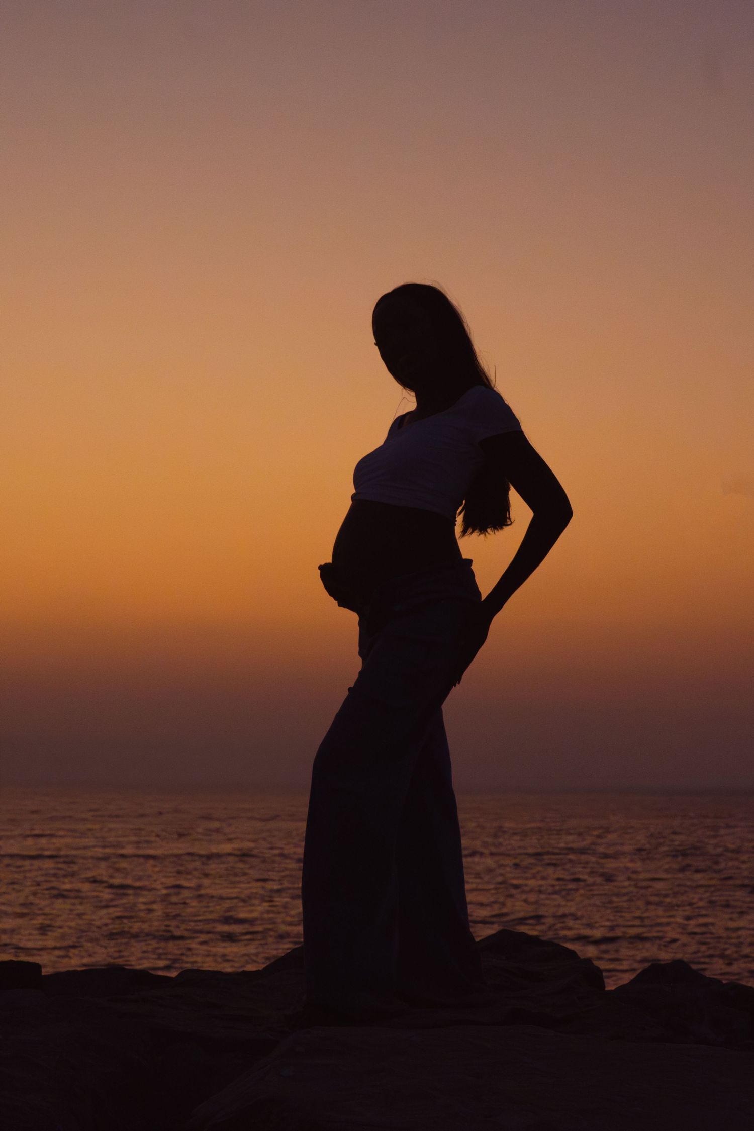Maternity beach photoshoot in Dubai – silhouette of pregnant woman at sunset by the sea, gender reveal
