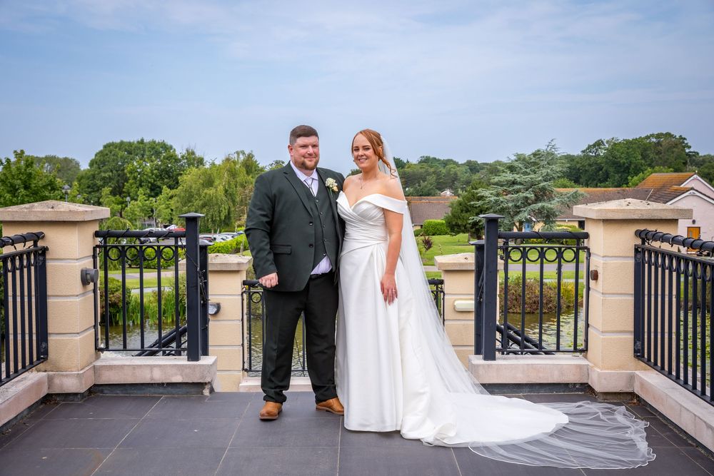 Bride and groom pose together on a balcony with scenic garden views on their wedding day.