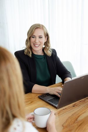 Professional working on laptop at wooden desk talking to a client, branding photography