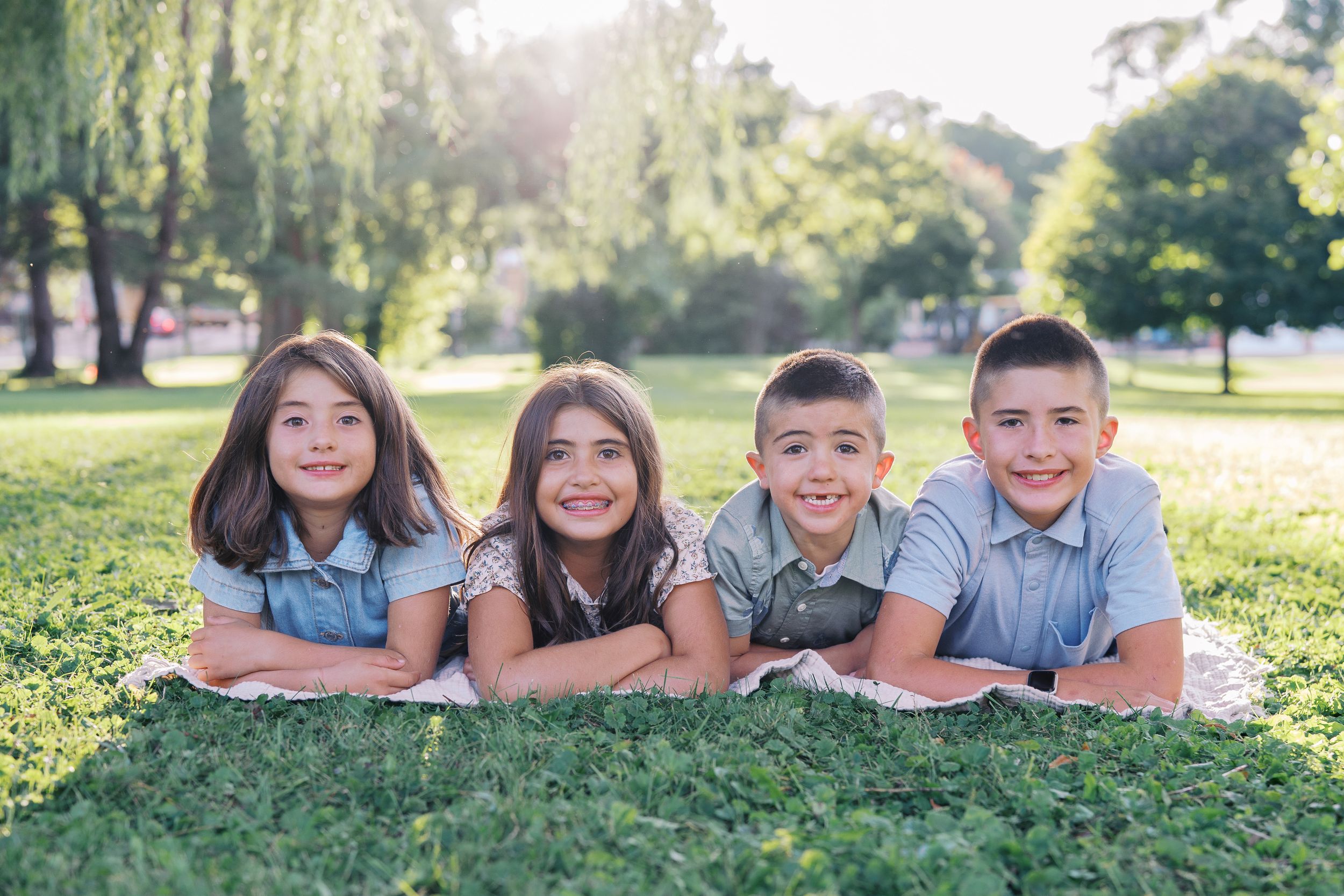 Children lying on grass posing for a casual outdoor photo session.