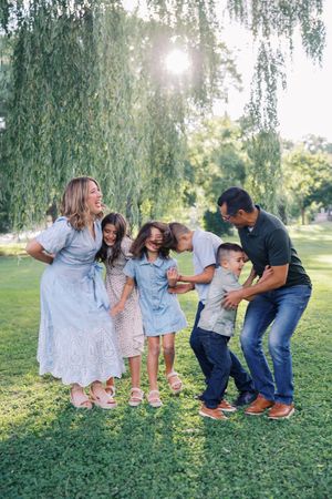 A candid family moment showing joyful interaction and laughter on a grassy hill.