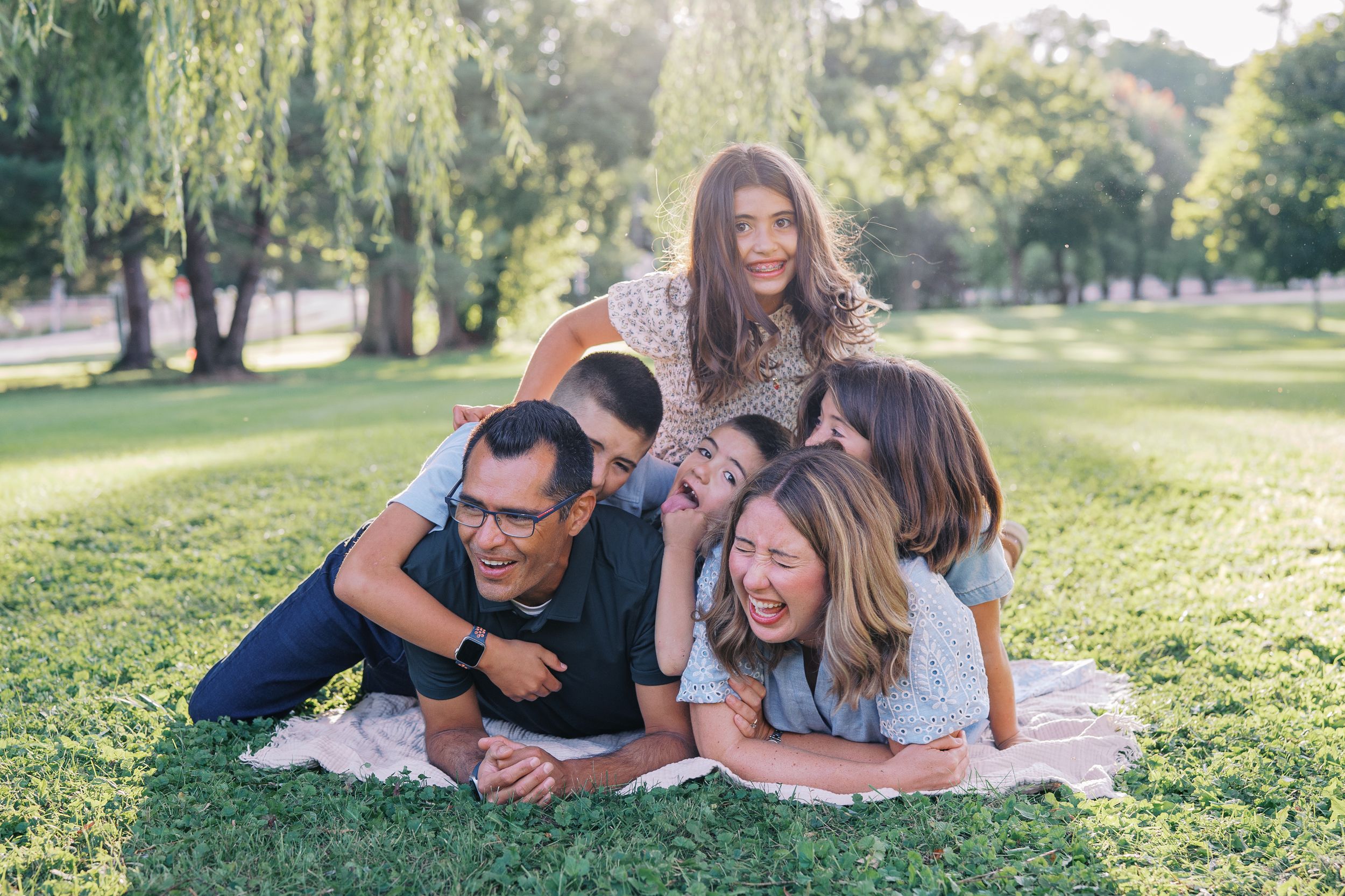 Family members relaxing together on grass during an outdoor photo shoot.