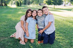 Children share joyful moments together while playing on green grass under a willow tree.