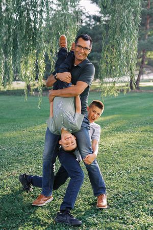 A playful sequence of photos showing a fun interaction between two people under a willow tree in a park setting.
