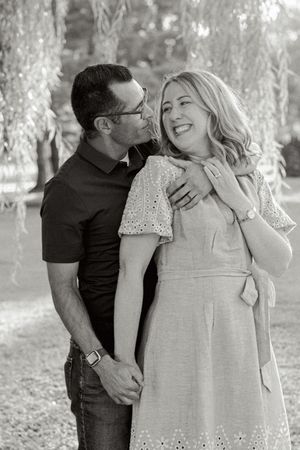 A black and white series of intimate family moments captured outdoors under trees.