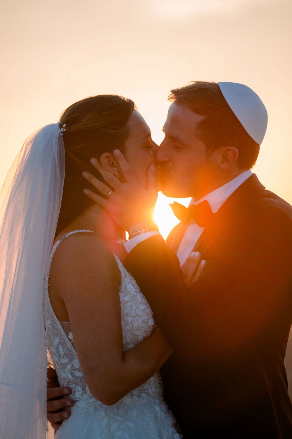 Silhouetted couple in wedding attire share romantic kisses at sunset in a series of four connected photos.