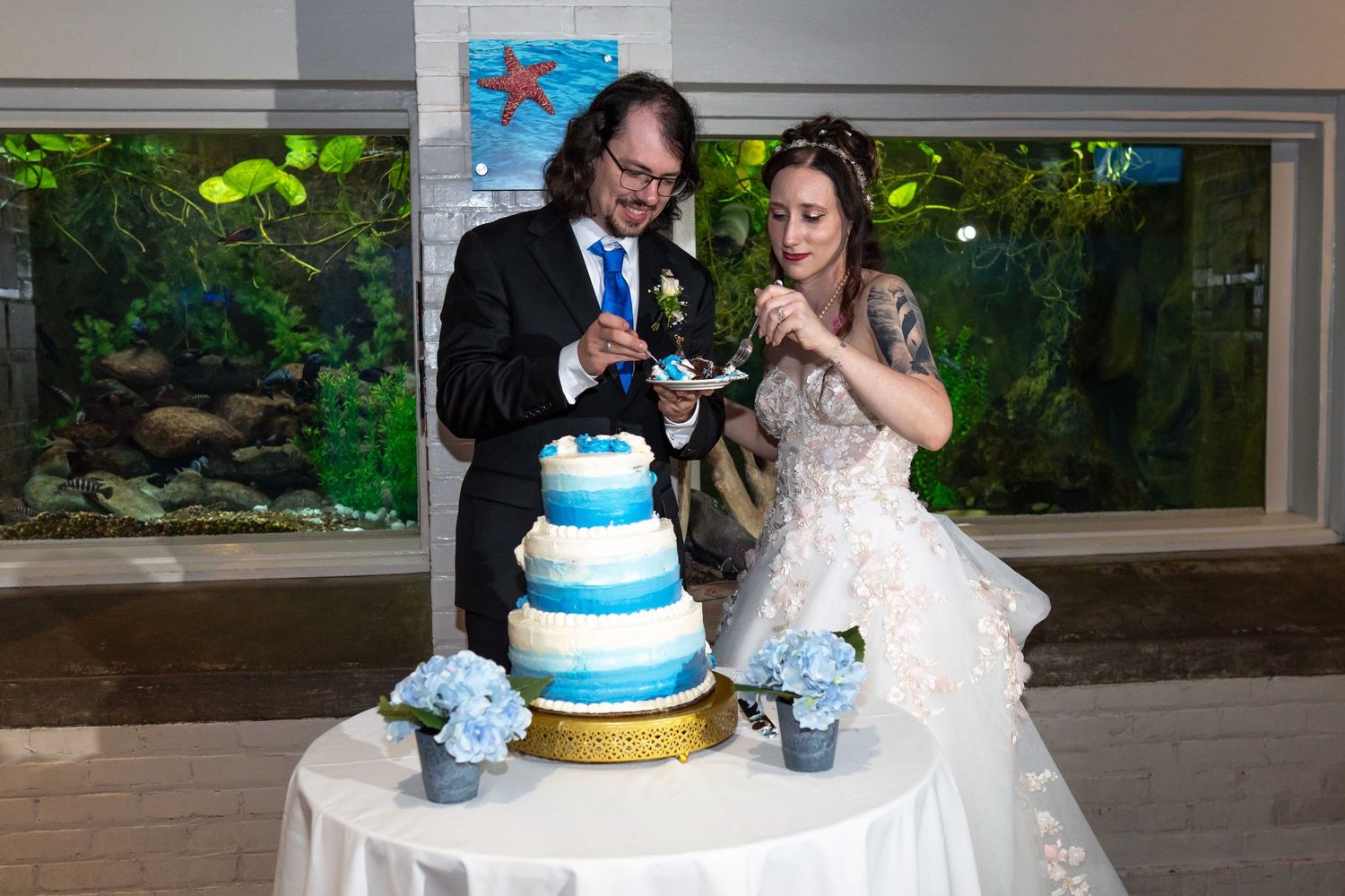 Bride and groom cutting a wedding cake at an aquarium venue reception Toledo Zoo Wedding Venue