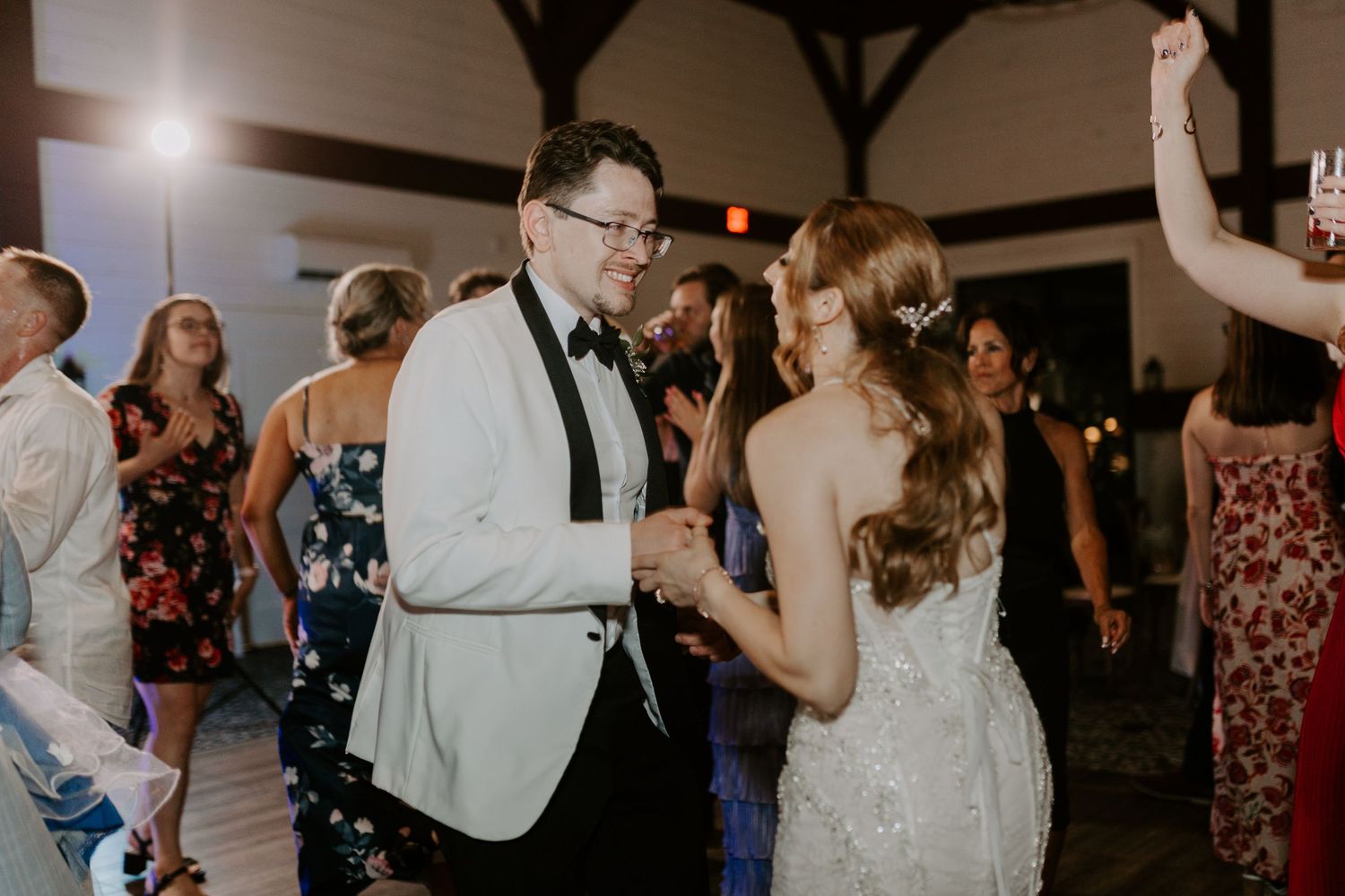 Bride and groom share a joyful dance together at their wedding reception surrounded by guests.