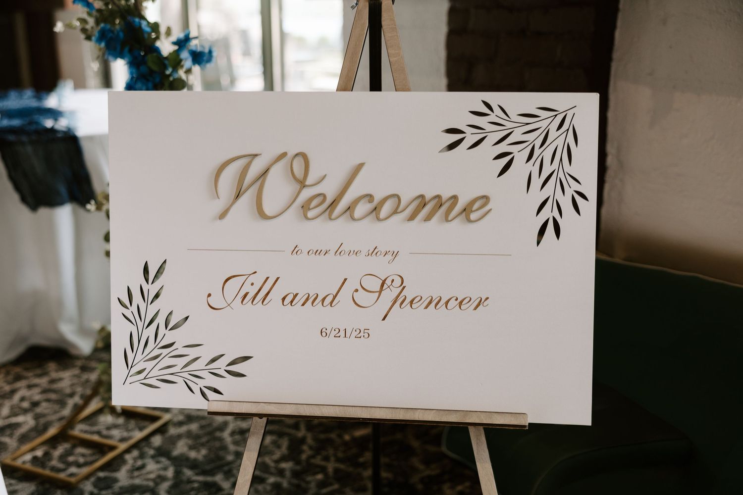 Elegant gold and white wedding welcome sign for Jill and Spencer on June 21, 2025 on a wooden easel.