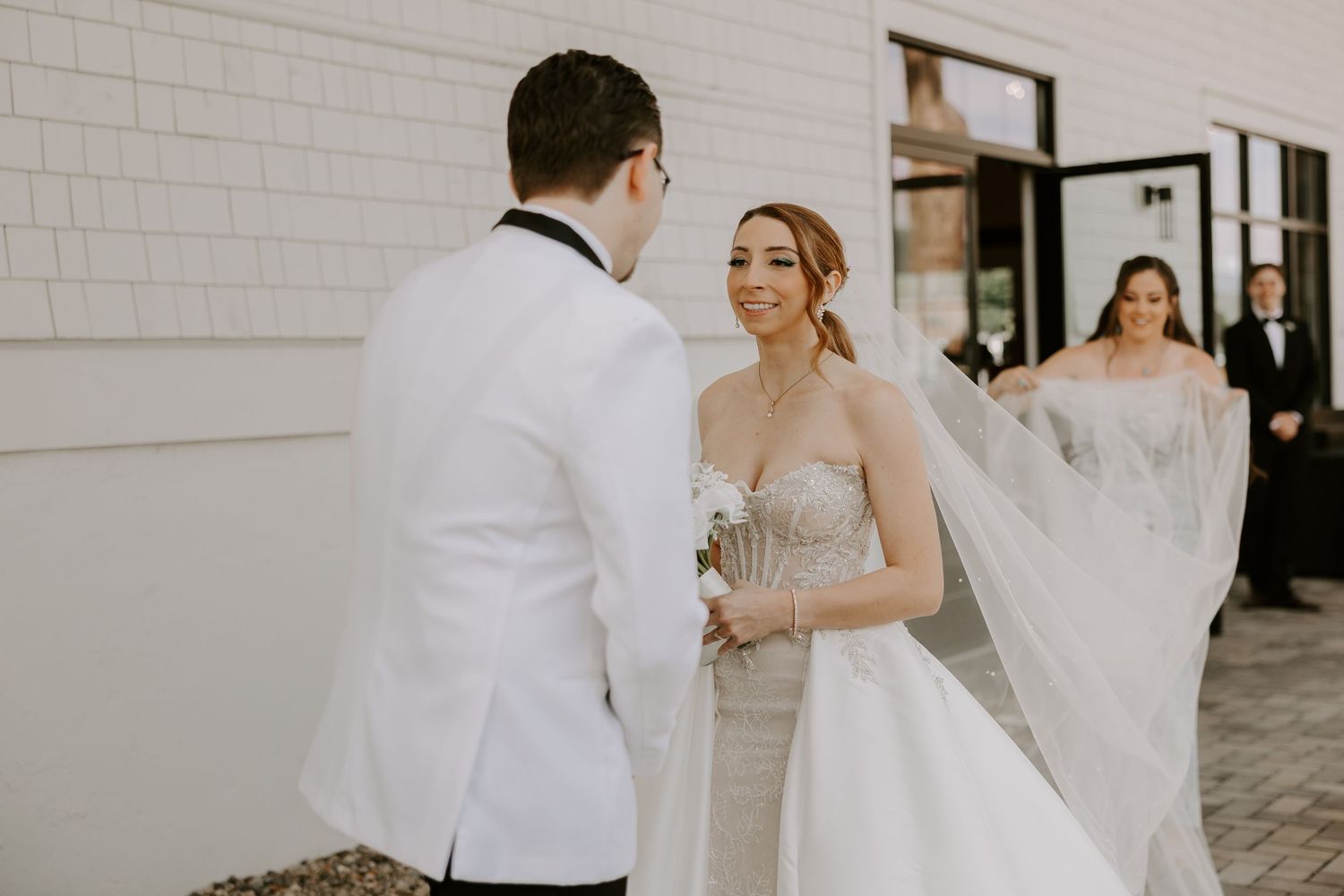 Bride smiling joyfully at groom during an emotional outdoor first look at The Carriage House wedding venue.