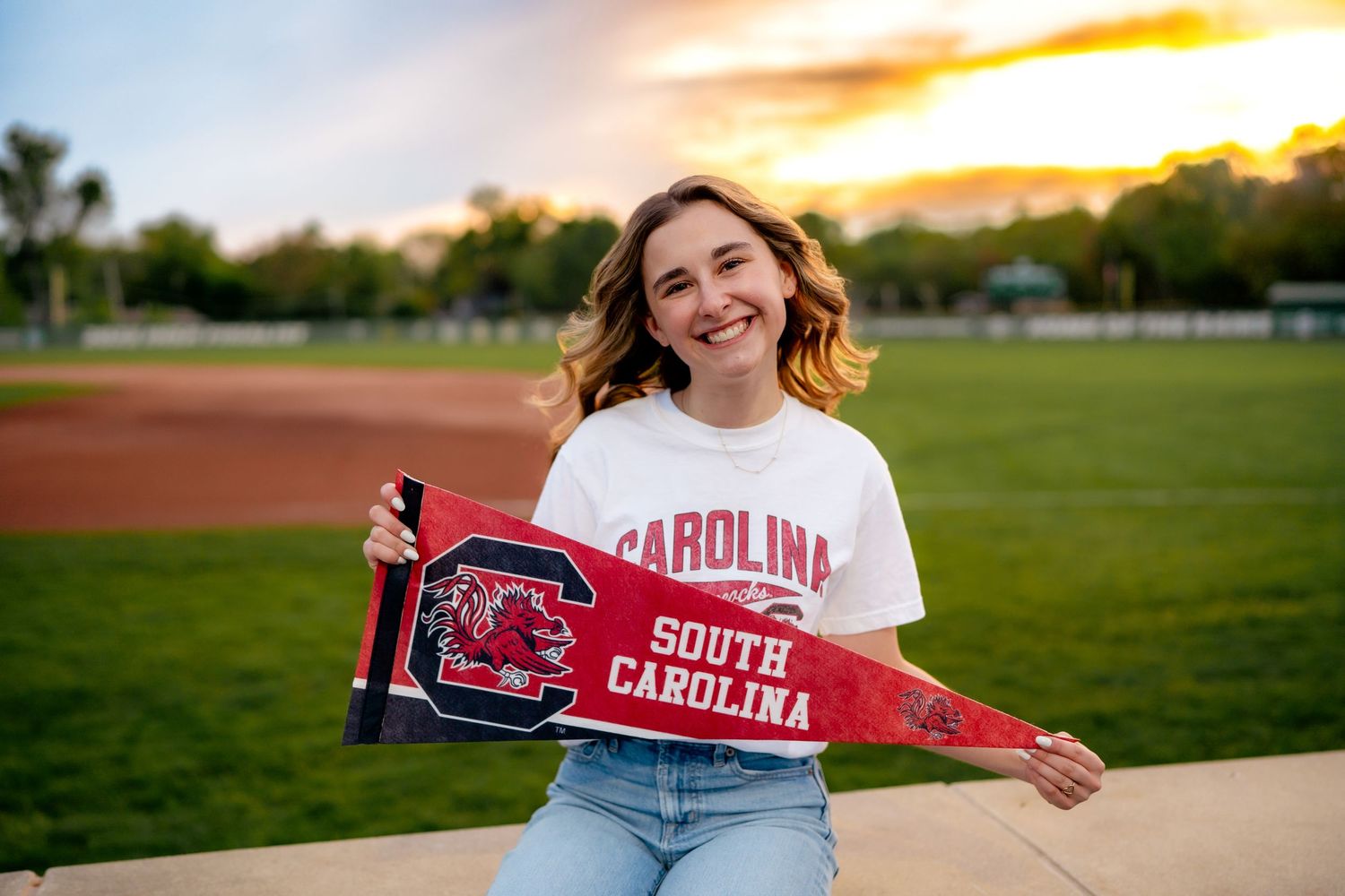 A person wearing University of South Carolina gear poses outdoors at sunset in a grassy field.