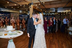 Wedding reception in a rustic indoor venue with wooden floors and string lights illuminating dancing guests.