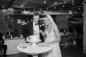 Bride and groom share a romantic moment during their first dance at a rustic barn wedding reception with twinkle lights.