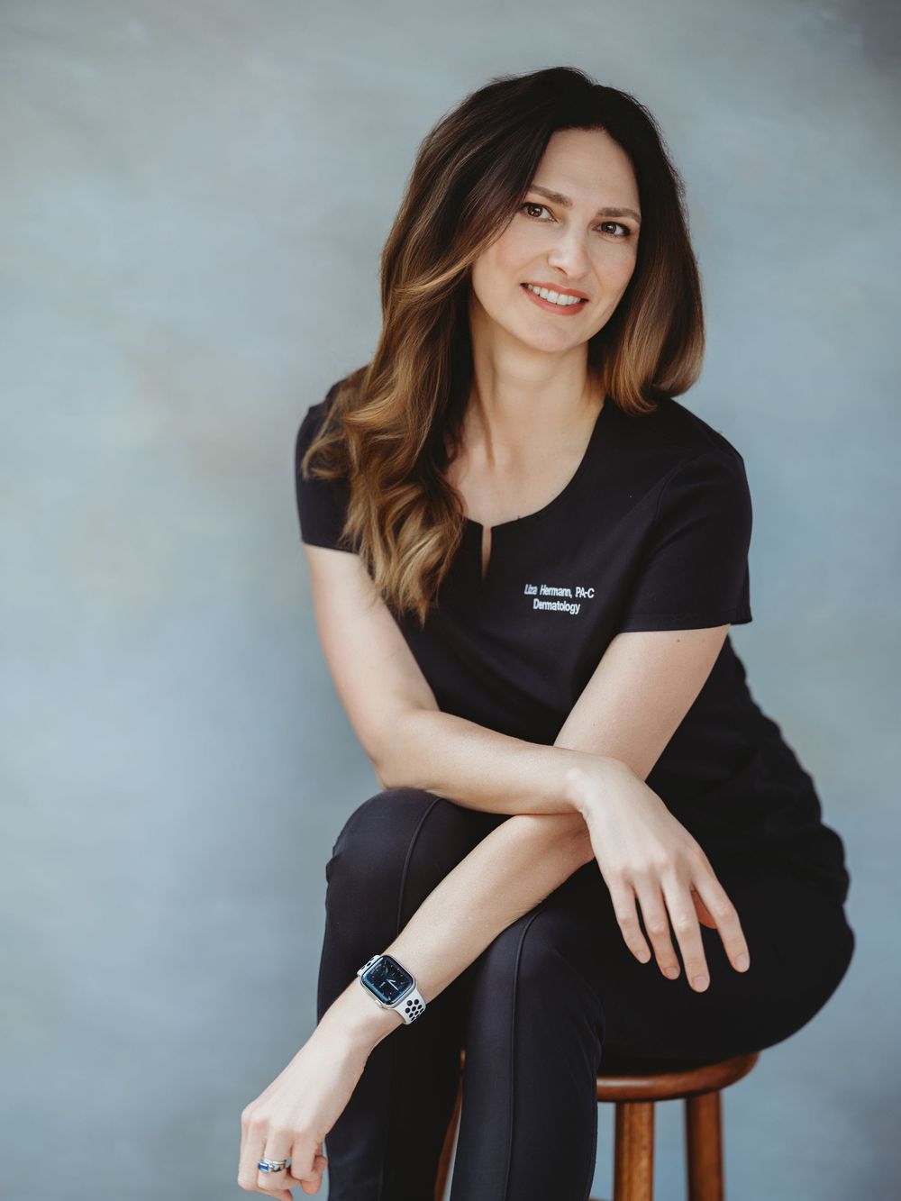 Professional portrait photography series showing someone in black attire posing on wooden stool against grey backdrop.