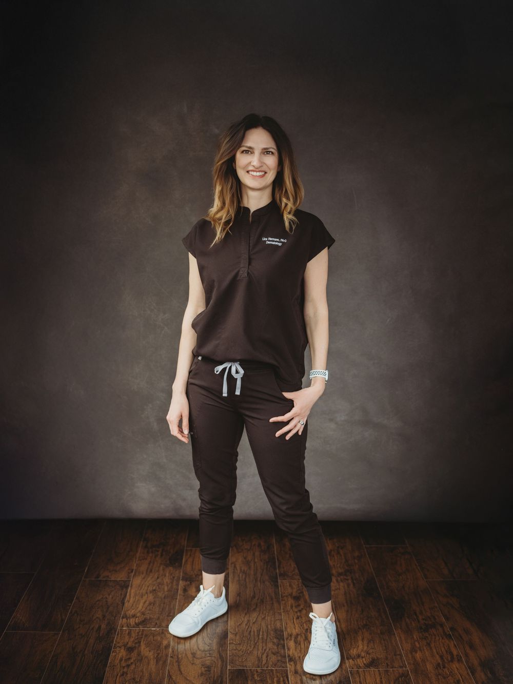 Full-length studio shots in black athletic wear and white sneakers on wooden floor.