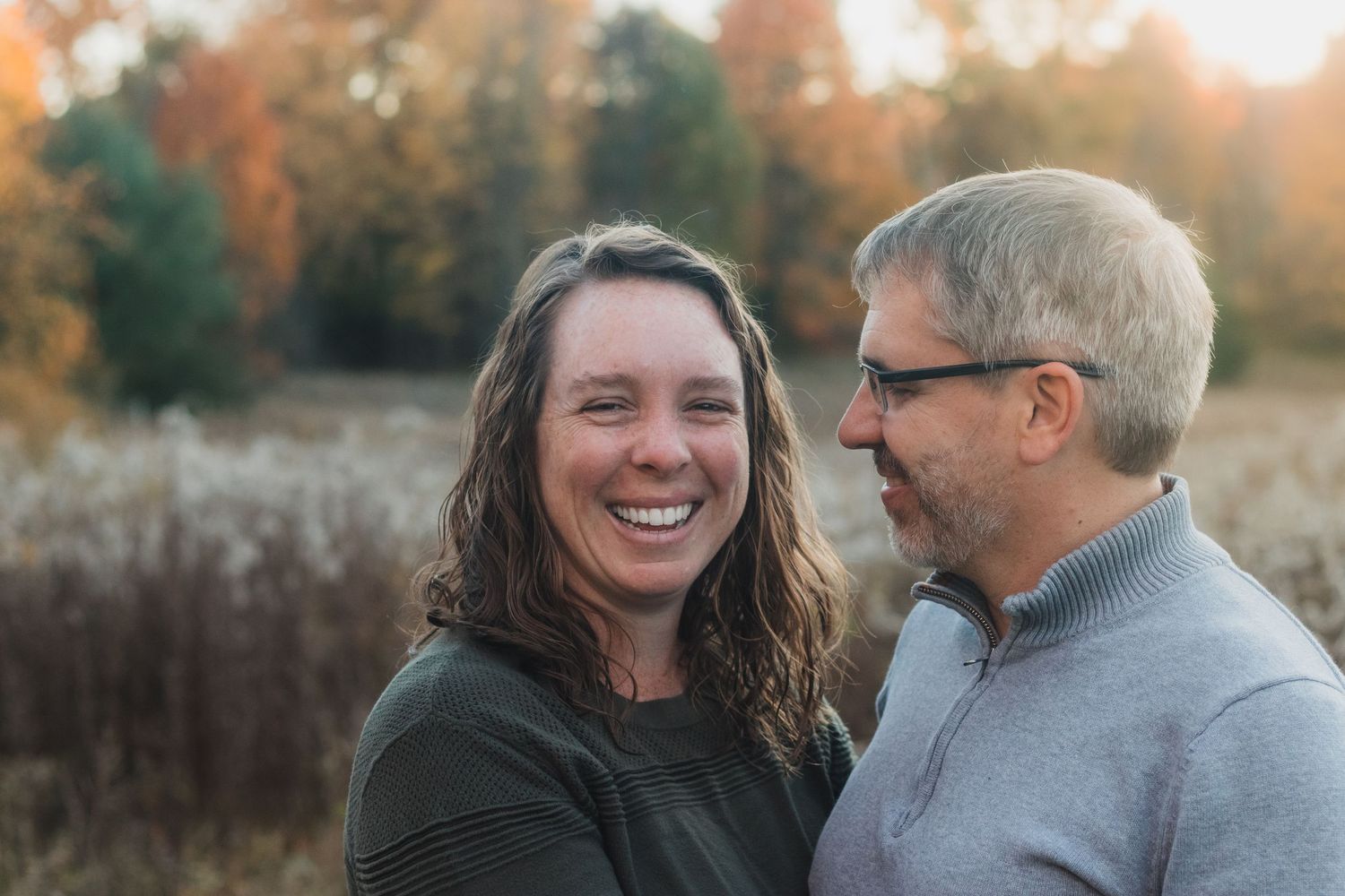 Husband looking lovingly at wife while she smiles during a golden hour lifestyle family photography session in Farmington Hills, Michigan.