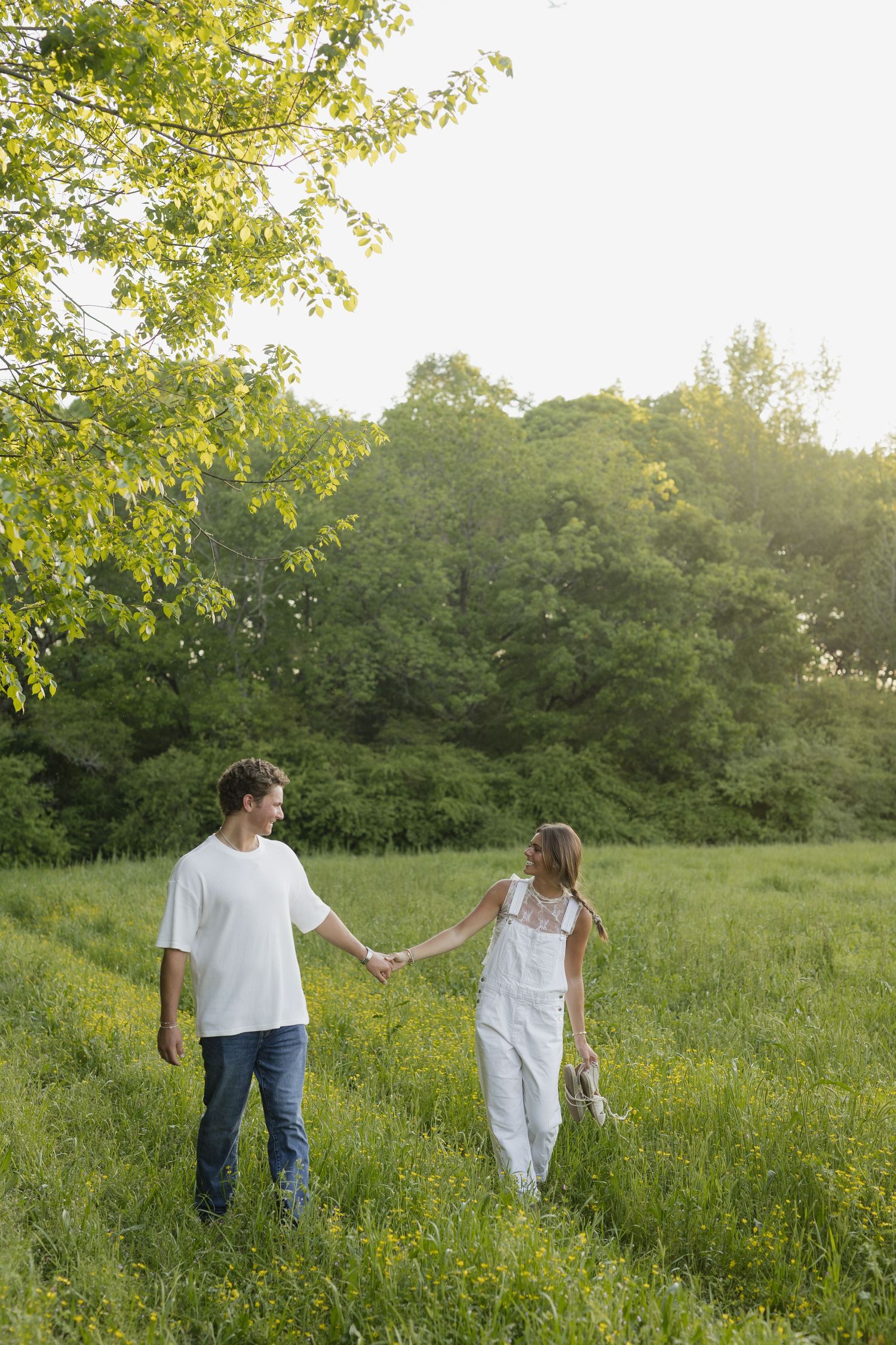 Couple walking and laughing together on path through pine forest wearing coordinated blue outfits.