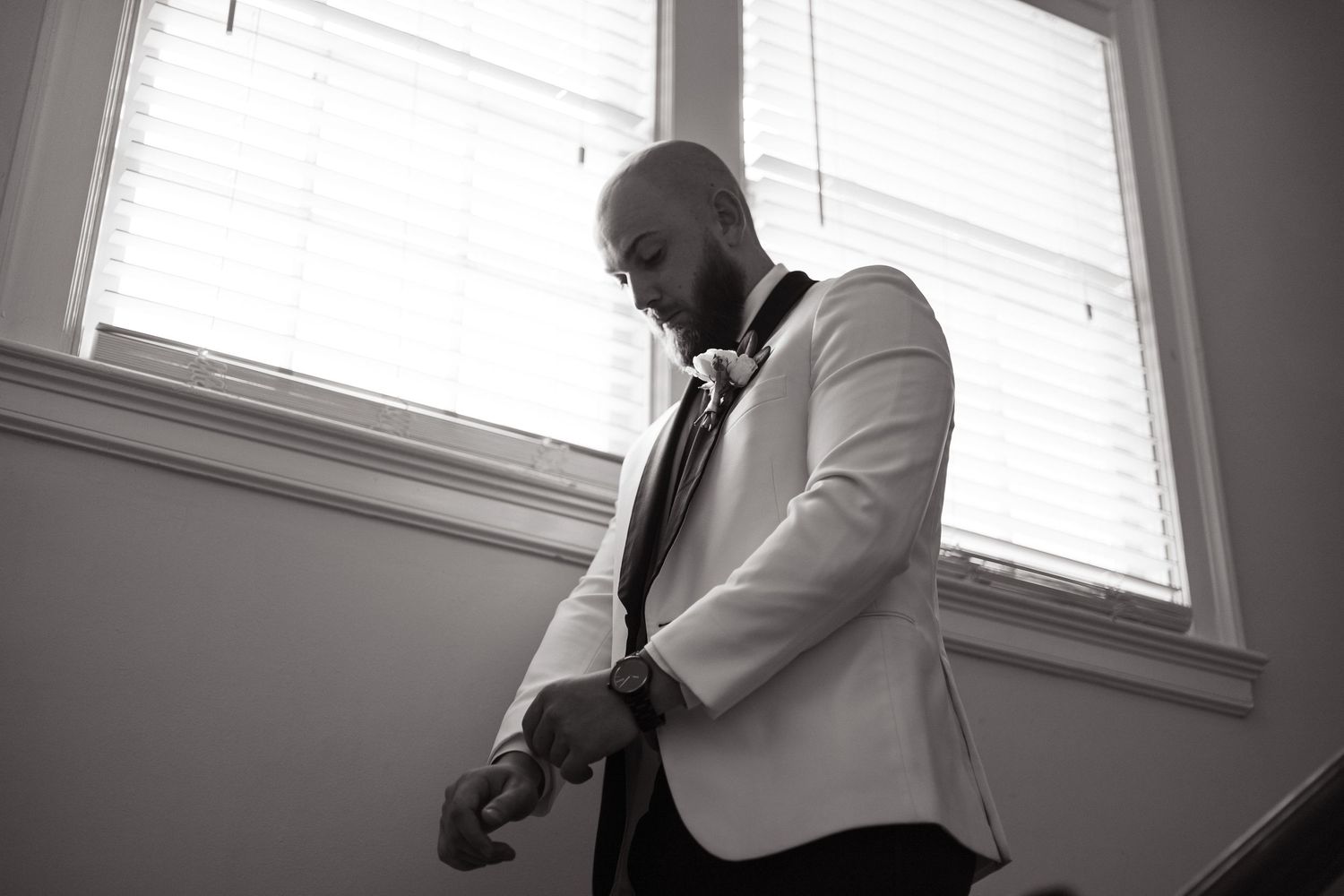 Monochromatic sequence of four connected photos showing someone in formal attire posing near a window.