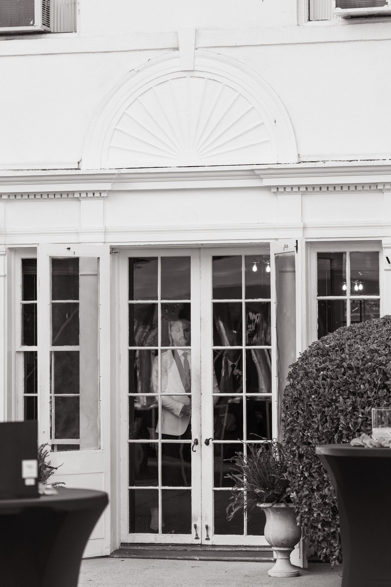 Elegant French doors with fanlight window and classical trim details at a wedding venue in black and white.