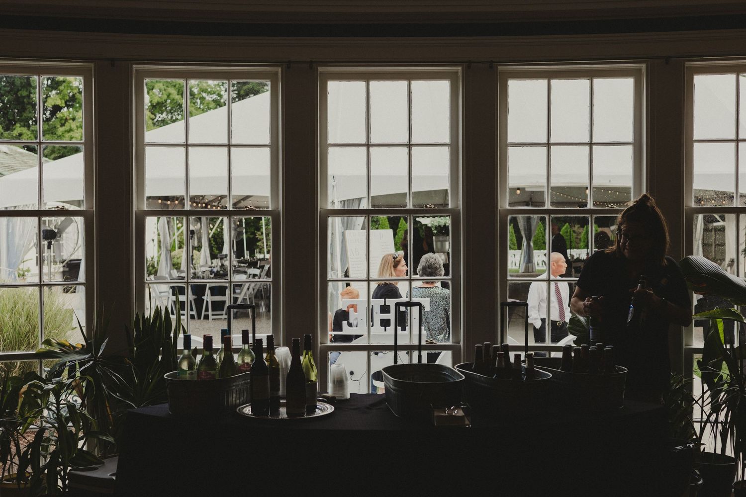 Interior view of a modern greenhouse-style venue with large windows streaming natural light into the open space.