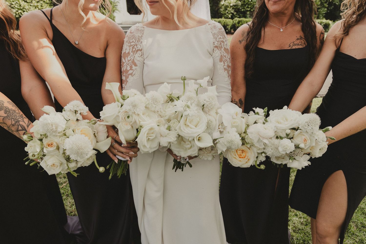 Black and white wedding photo showing bridesmaids and bride holding elegant white floral bouquets.