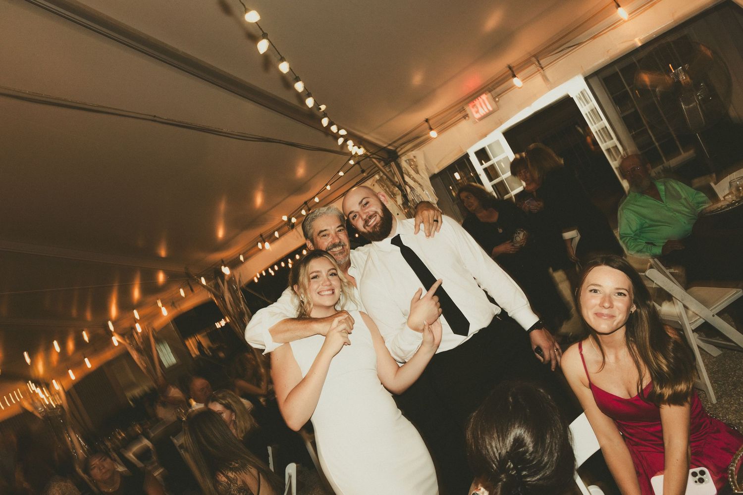 Partygoers dance and celebrate on a crowded dance floor under warm lighting in an indoor venue at night.