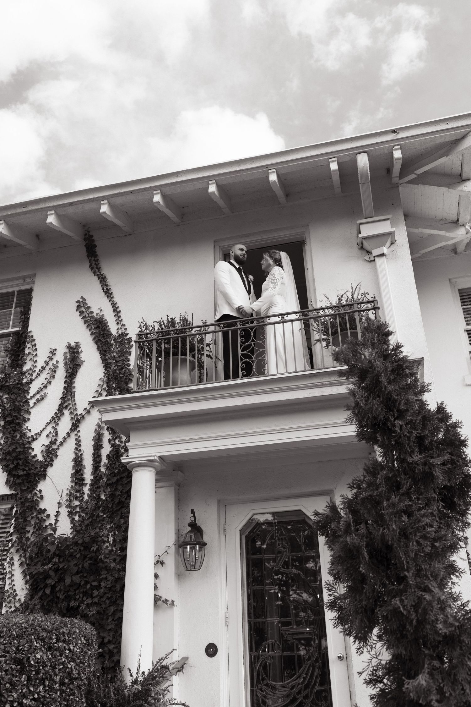 A white colonial-style facade with black shutters and ornate wrought iron balconies adorns this elegant building exterior.