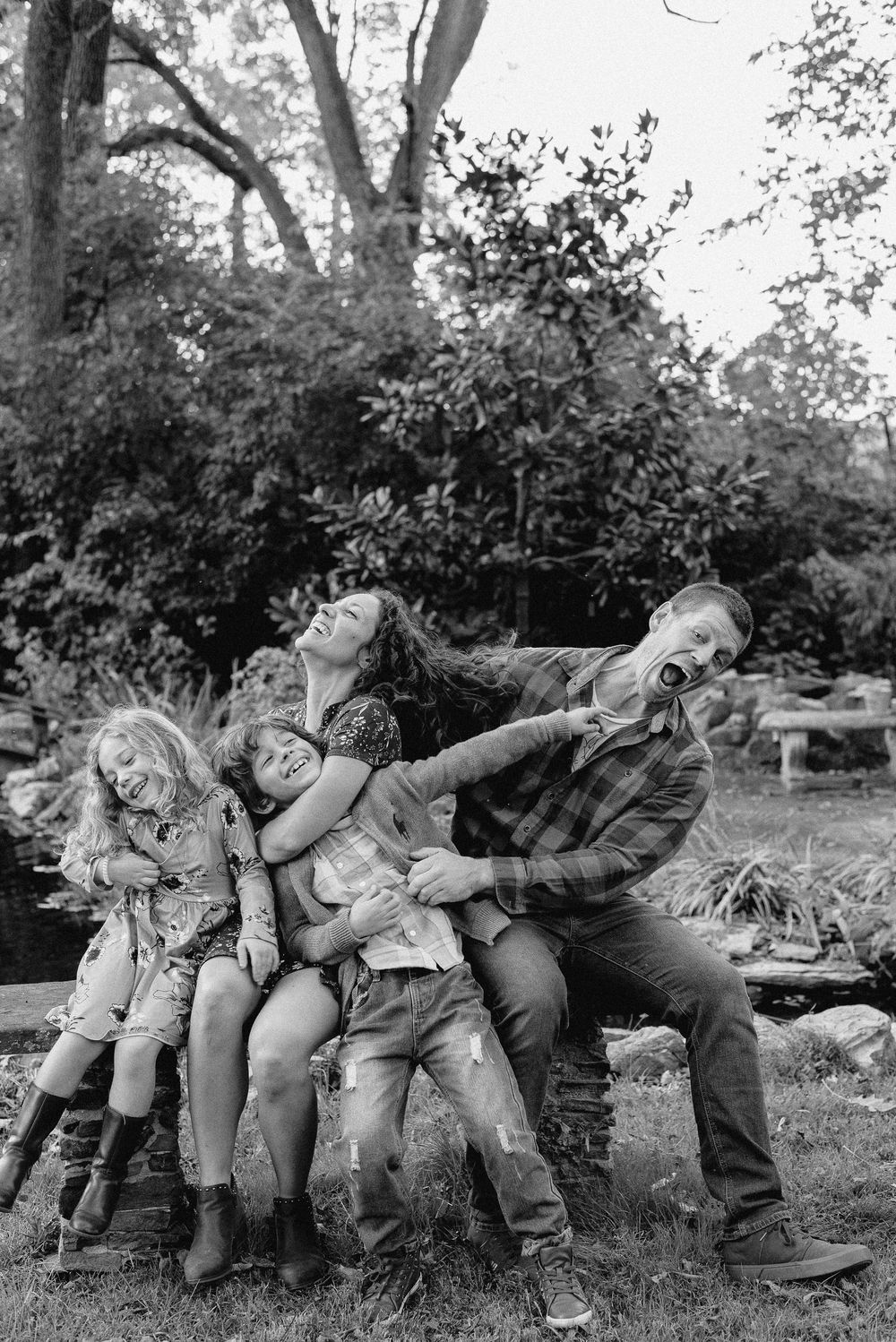 A playful black and white candid shot of a family being silly together outdoors.
