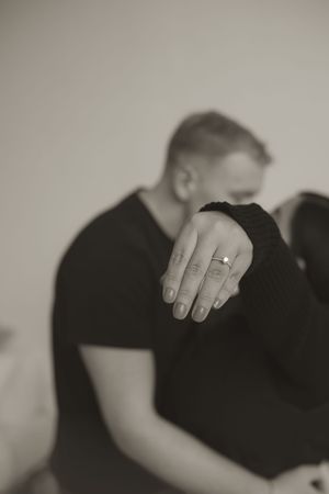 An artistic black and white photo focusing on hands and an engagement ring during an intimate moment.