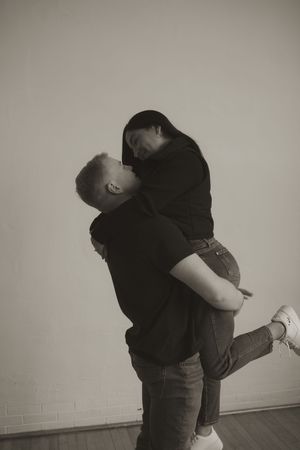 A black and white artistic portrait capturing an intimate embrace against a minimalist background.
