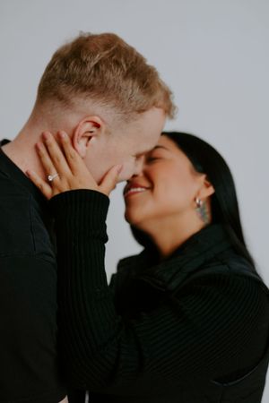 Intimate couple in black clothing share tender moments against light background in artistic photo series.