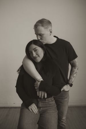 Artistic black and white portrait of couple embracing on wooden floor.