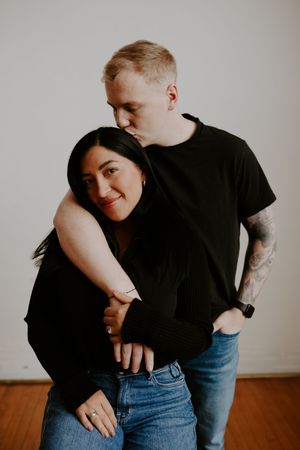 Playful couple in casual wear share intimate moments during indoor photo session.