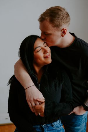 Romantic couple shares tender moments in a minimalist indoor setting.