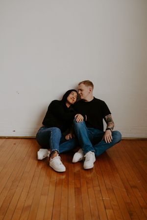 Candid moments between couple lounging on wooden flooring.