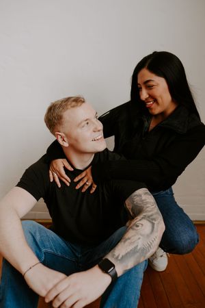 Joyful couple laughs together during casual indoor photoshoot.
