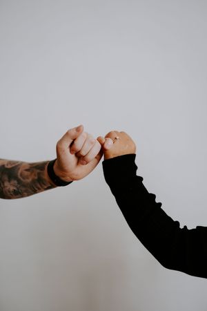Close-up of tattooed arm reaching across grey background.