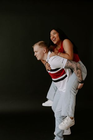 A couple shares an intimate moment against a dark background wearing white and red clothing.