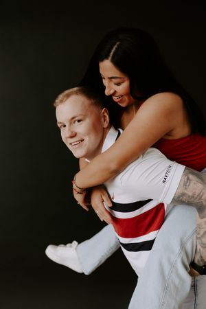 Two people embrace playfully while wearing contrasting white and red outfits.