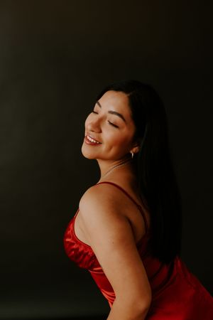 Woman in red dress laughs joyfully during intimate portrait session.
