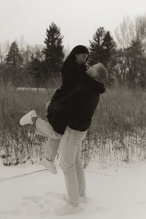 Two people play in snowy field wearing winter clothing.