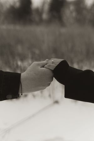 Hands extend toward each other against snowy landscape background.