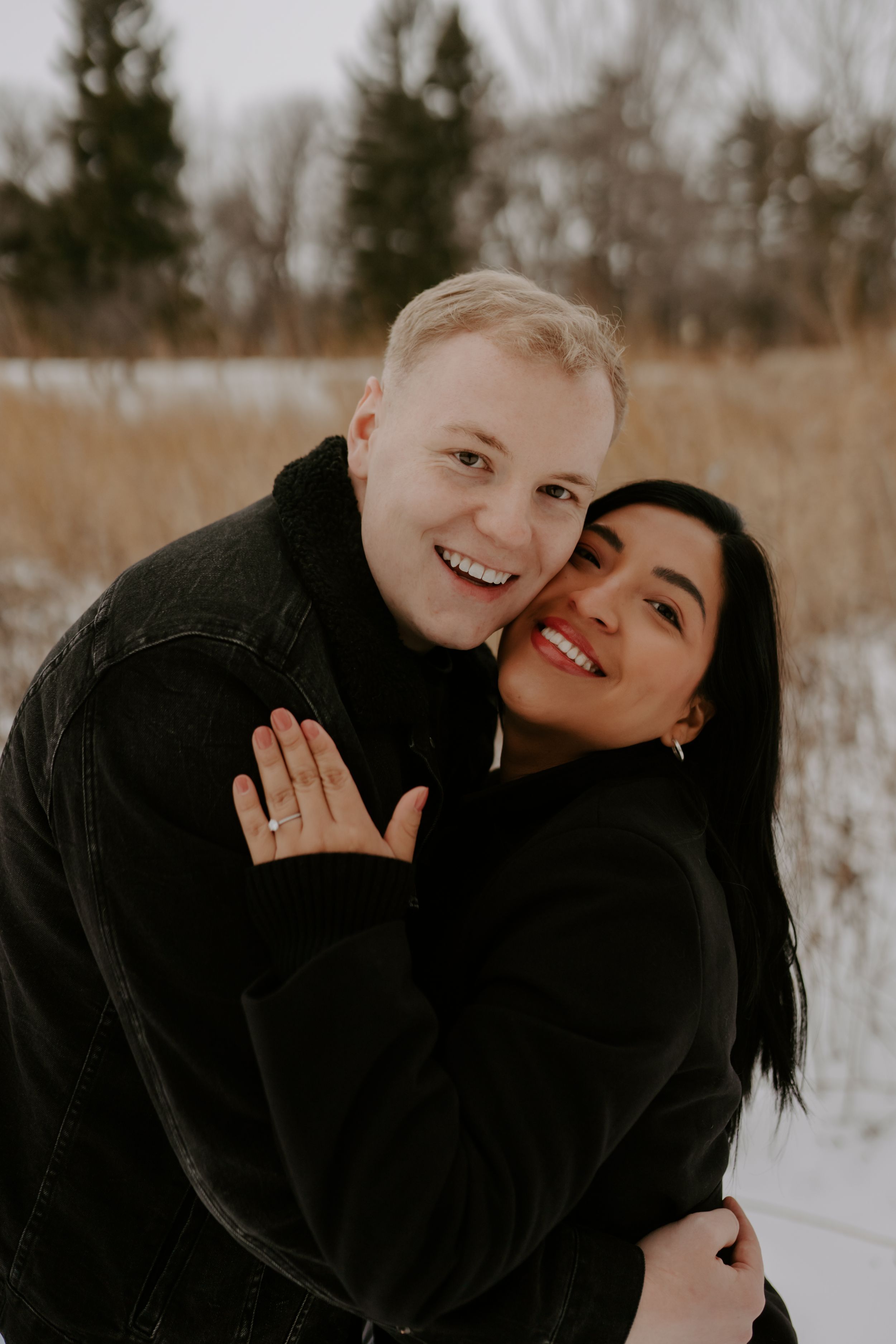 Candid winter engagement photos of a couple showing affection and joy in a snowy landscape.