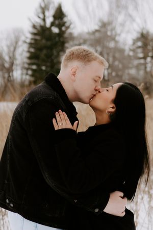 A romantic winter engagement photo of a couple sharing a tender moment outdoors.
