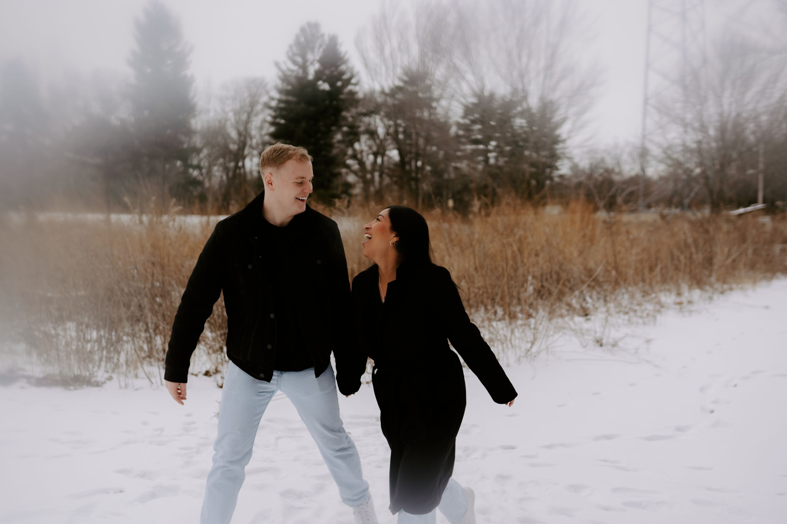Couple enjoying a playful moment together in a snowy field during winter.