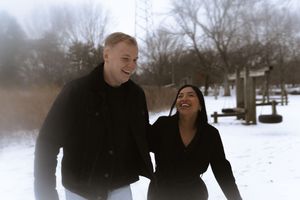 A couple shares a tender moment together in a snowy winter landscape.